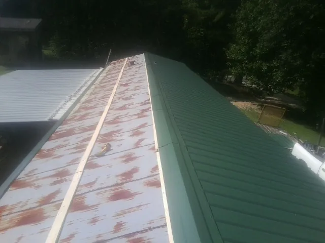 Old rusted panels beside newly installed green metal roofing — Wind Damage Roof Repair by Roofing Brothers in Isle Of Palms