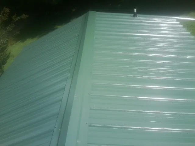 New green metal panels meeting at the ridge of a roof — Flat Roof Repair work by our crew in Isle Of Palms