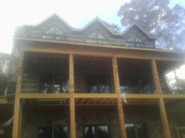 Dormers and porch framing on a large log home under construction — Roof Coating work by our crew in Isle Of Palms
