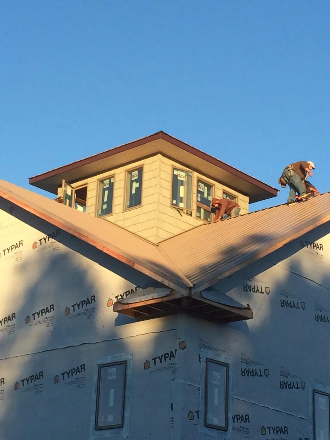 Roofers working around a rooftop cupola on a new metal roof at sunset — Roof Waterproofing in Isle Of Palms by Roofing Brothers